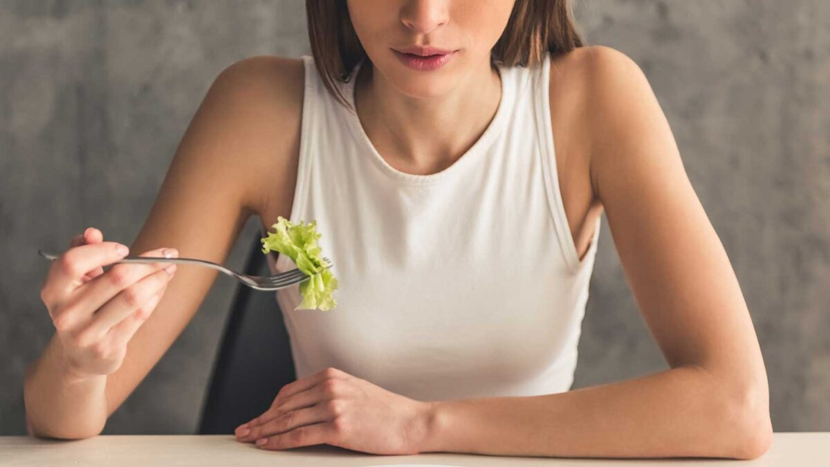Woman eating a salad. Negative body image, low self-esteem, and using disordered eating as a coping mechanism contribute to eating disorders.