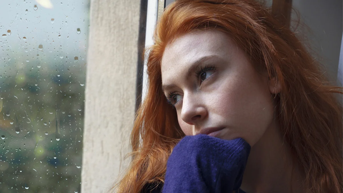 Woman depressed staring outside of window