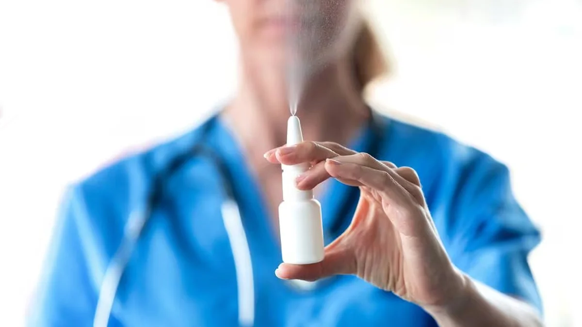 Woman in blue scrubs with esketamine nasal spray.