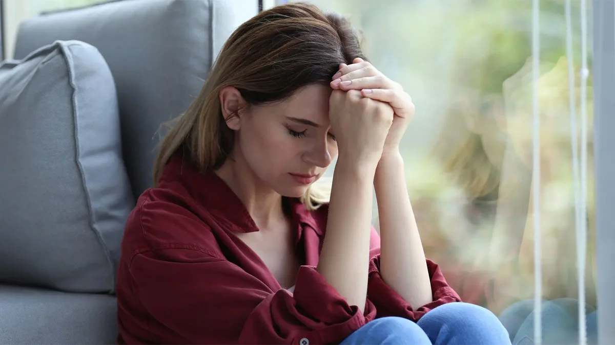 Woman sitting next to a window.